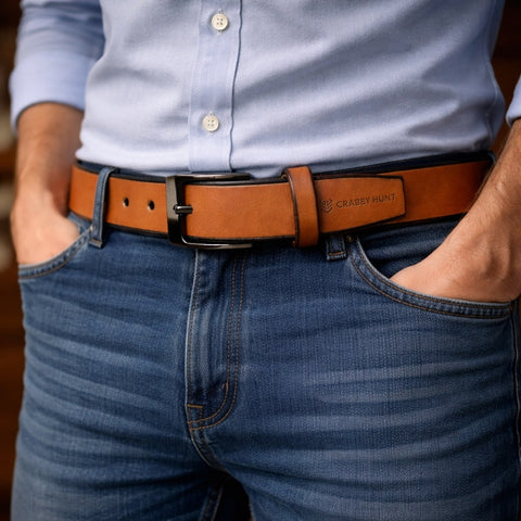 Person wearing a brown belt with a visible brand logo, blue jeans, and a light blue shirt.